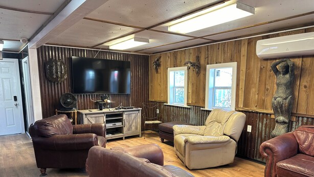 Un salon chaleureux avec des canapés en cuir, un meuble de rangement en bois et un téléviseur à écran plat.