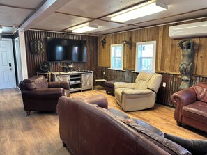 A cozy living room with leather sofas, a wooden entertainment unit, and a flat-screen TV. - Sausalito South- Spacious, Comfortable, and Clean Houseboat (Venice)