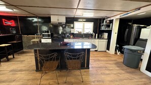 Une cuisine dotée d’un îlot central, de chaises en bois, d’un four à micro-ondes, d’une cuisinière et d’un réfrigérateur.