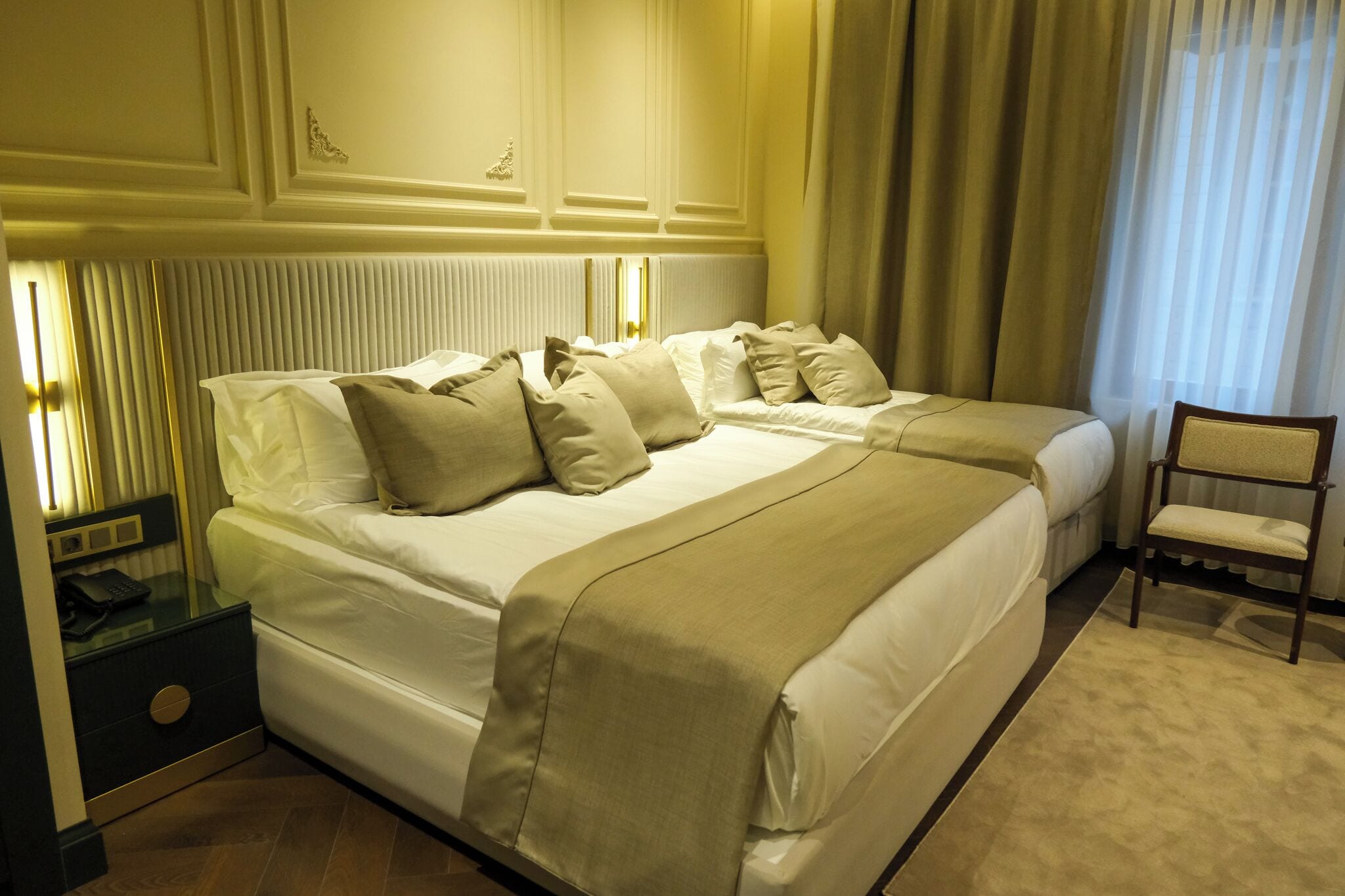 Ein Hotelzimmer mit zwei Betten, einem Nachttisch, einem Sessel und einer Heizung.