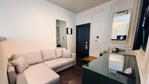 A modern living room with a sofa, a glass coffee table, a black door, and a mirror. - Sur Royals Hotel's (Diyarbakir)