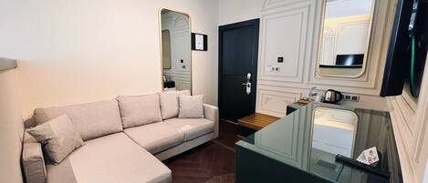 A modern living room with a sofa, a glass coffee table, a black door, and a mirror.