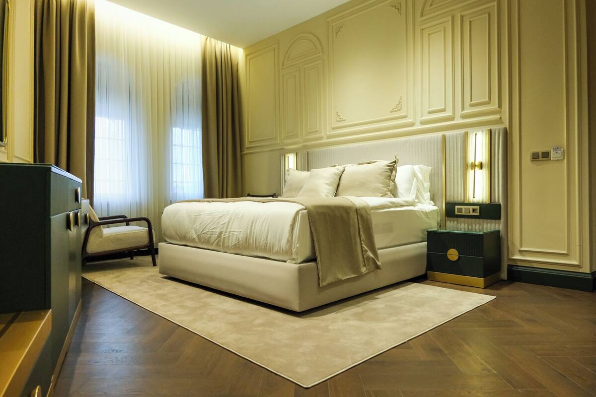 A bedroom with a large bed, a nightstand, a chair, and a dresser.