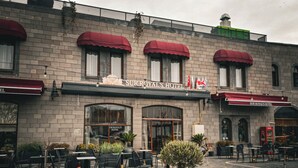 A hotel exterior with red awnings, outdoor seating, and a sign reading "Sur Royal's Hotel". - Sur Royals Hotel's (Diyarbakir)