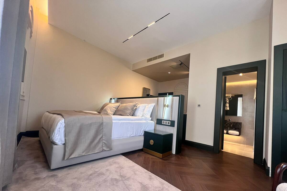 A modern bedroom with a large bed, a bedside table, and a walk-in closet.
