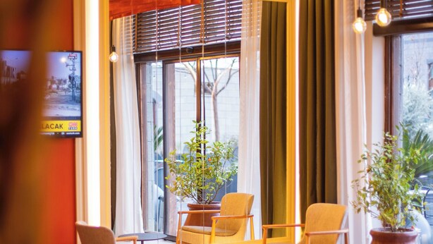 A cozy room with a large window, two chairs, a small table, and a potted plant. - Sur Royals Hotel's (Diyarbakir)