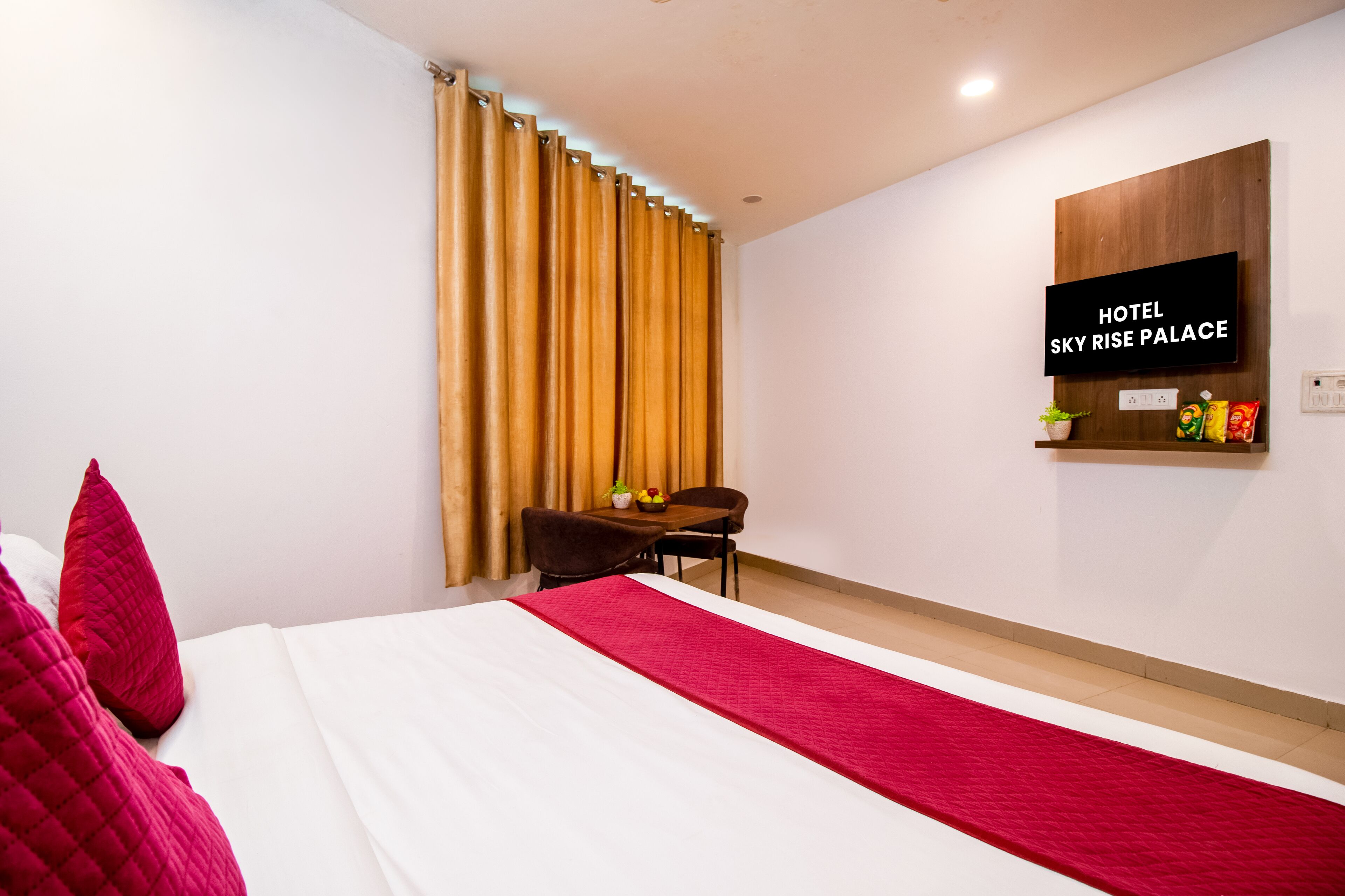 Een hotelkamer met een bed, bureau, stoel, televisie en een raam met gordijnen.