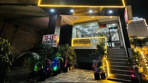 A hotel entrance with a neon sign, a staircase, and potted plants. - Hotel S.R. Plaza (New Delhi)