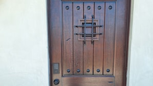 A wooden door with a keypad lock and a metal latch.
