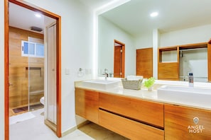 A modern bathroom with wooden cabinets, a large mirror, and a white sink.