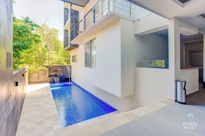 A modern building with a swimming pool, a balcony, and a trash bin.