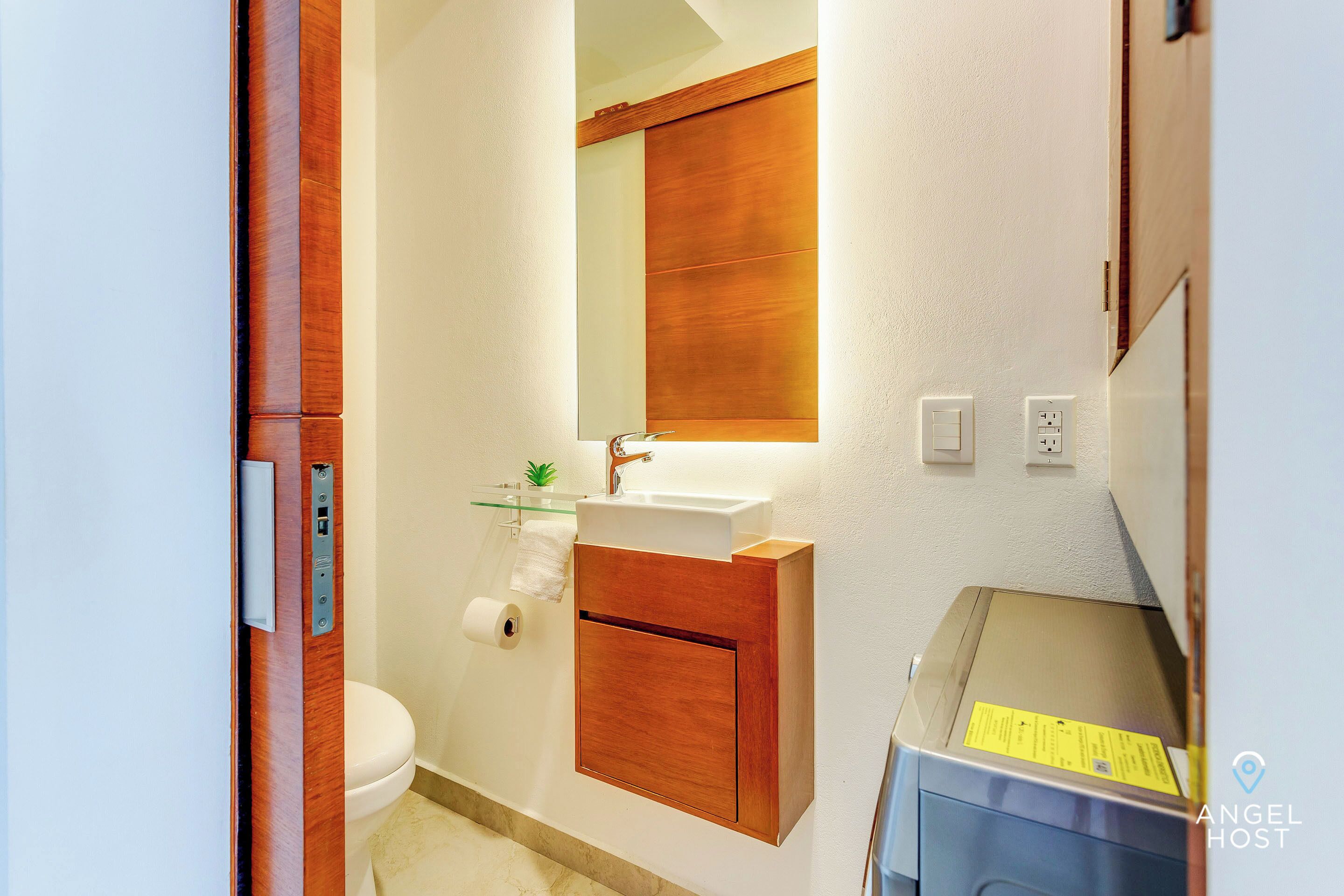 A bathroom with a wooden vanity, a mirror, a sink, and a toilet.