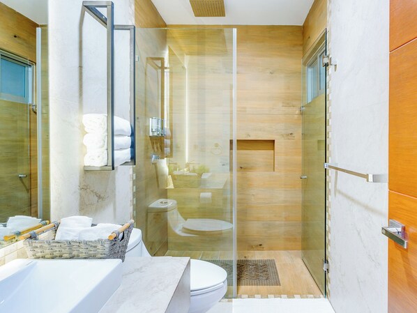 A modern bathroom with a glass-enclosed shower, a wooden vanity, and a toilet.