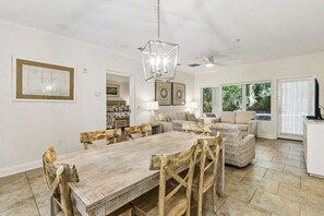 A spacious living area with a dining table, sofas, and a television.