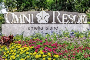 A sign for Omni Resort Amelia Island with a floral garden in front.