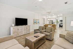 A living room with a flat-screen TV, a wooden coffee table, and patterned sofas.