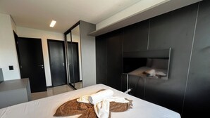 Ett modernt hotellrum med en stor säng, en inbyggd TV och en garderob med skjutdörrar.