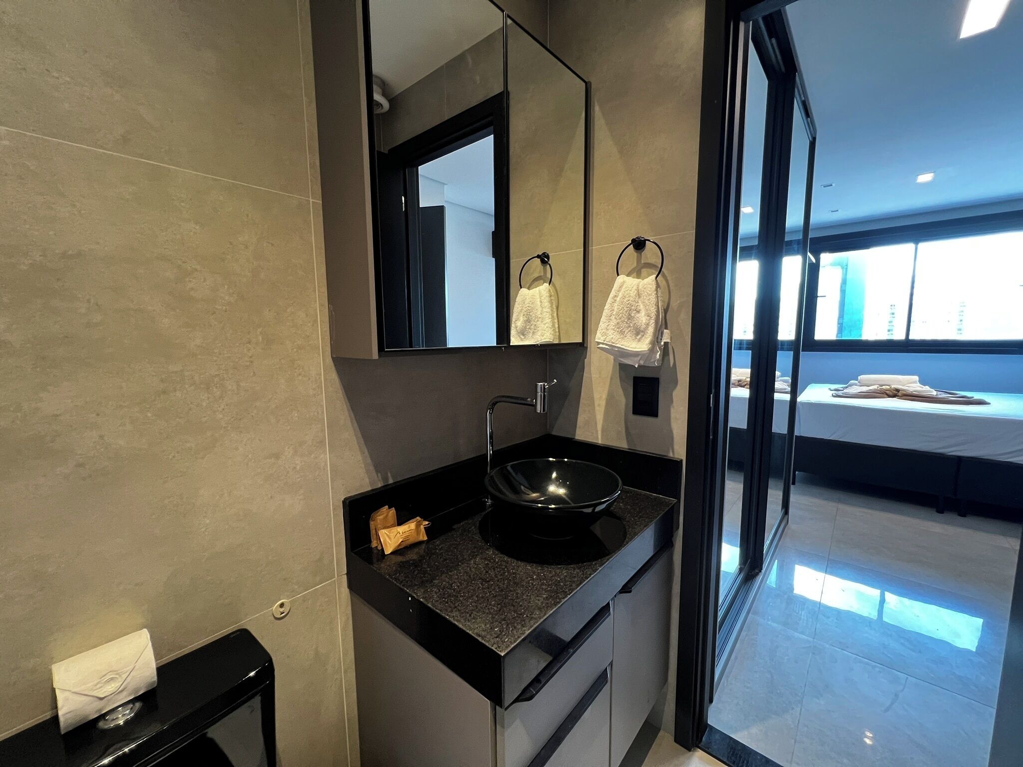 Un baño moderno con un lavamanos negro, un espejo y un perchero para toallas.