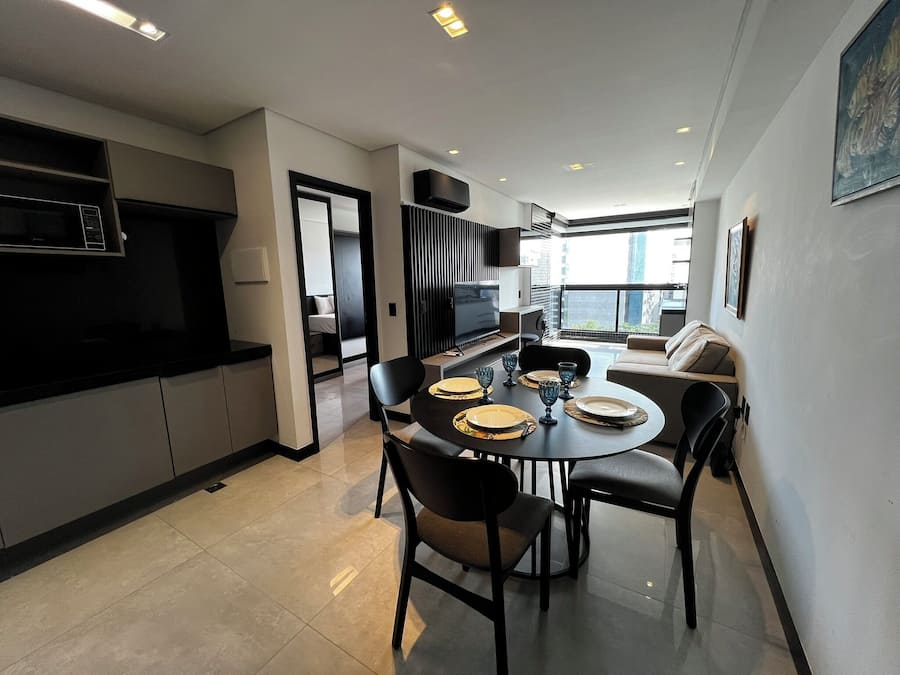 A modern kitchen with a dining area, a sofa, and a TV.