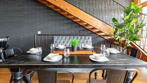 A dining area with a black table, grey upholstered bench, and a wooden staircase. - Uniquely Nashville, this Property has Amazing Views, A great Location to Unwind (Nashville)