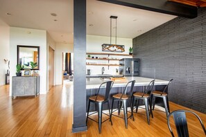 Une cuisine moderne dotée d’un îlot central, d’un coin bar et d’un mur d’accent en briques.