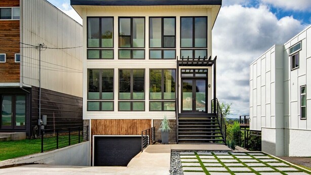 A modern two-story house with a garage, large windows, and a staircase leading to the upper floor. - Uniquely Nashville, this Property has Amazing Views, A great Location to Unwind (Nashville)