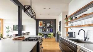 A modern kitchen with a central island, wooden flooring, and a wall adorned with framed artwork. - Uniquely Nashville, this Property has Amazing Views, A great Location to Unwind (Nashville)