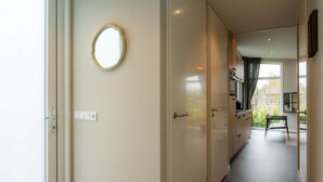Ein Flur mit einer Tür, einem Lichtschalter und einem Spiegel an der Wand.