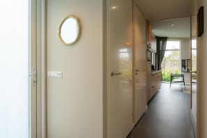 A hallway with a door, a light switch, and a window with a view of the outside.