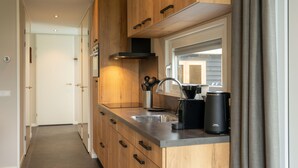 Eine moderne Küche mit Holzausstattung, einer Spüle aus Edelstahl und einer Kaffeemaschine.