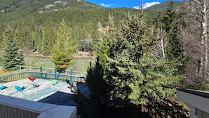 A deck with outdoor seating overlooking a forested valley and mountains. - Spacious Toby Creek loft with river and mountain views (Panorama)