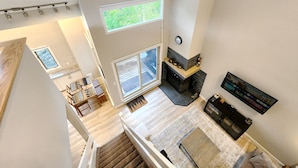 A spacious living area with a fireplace, a large window, and a TV mounted on the wall. - Spacious Toby Creek loft with river and mountain views (Panorama)