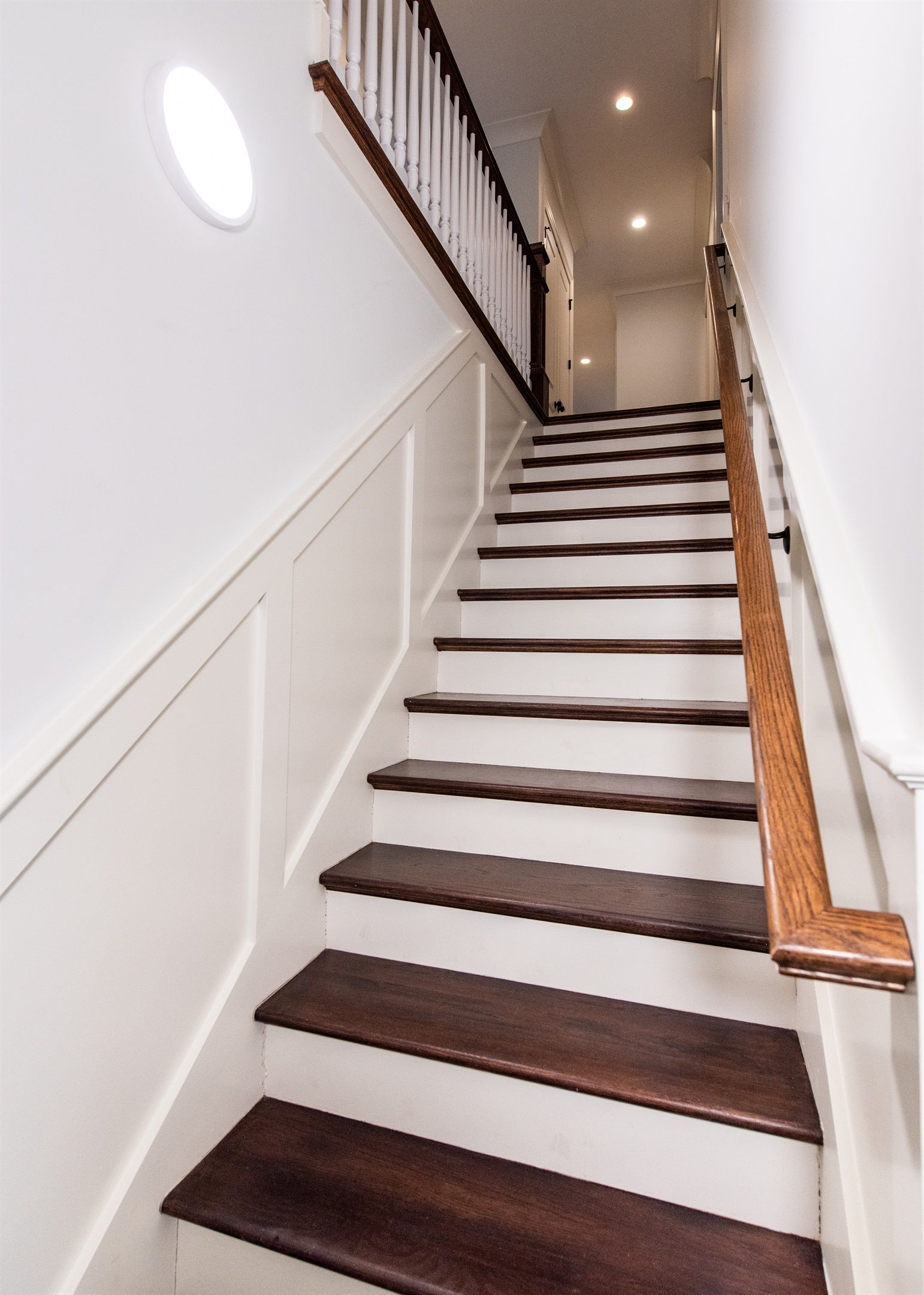 A staircase with white walls and dark wooden steps.