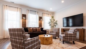 A living room with a brown sofa, two plaid armchairs, a wooden coffee table, and a large TV on the wall. - Pet Friendly, Pool, Shops, Downtown, Bourbon, Golf Local Dining, Fully Loaded (Prospect)