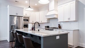 A modern kitchen with white cabinets, stainless steel appliances, and a central island with bar stools. - Pet Friendly, Pool, Shops, Downtown, Bourbon, Golf Local Dining, Fully Loaded (Prospect)