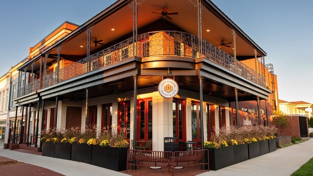 A two-story building with a balcony, a sign reading "Crust & Crumb Bakery & Cafe," outdoor seating, and a brick facade. - Pet Friendly, Pool, Shops, Downtown, Bourbon, Golf Local Dining, Fully Loaded (Prospect)