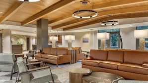 A spacious lobby with leather sofas, a coffee table, and a patterned carpet.