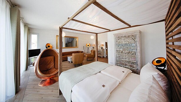 A modern hotel room with a canopy bed, a hanging chair, a desk, and a view of the city. - Appartement in Strausberg mit Fruehstueck Inklusive (Strausberg)