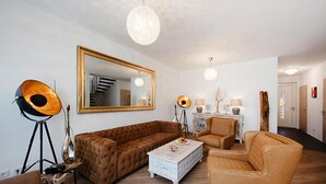 A living room with a large mirror, a brown sofa, a white coffee table, and a floor lamp. - Appartement in Strausberg mit Fruehstueck Inklusive (Strausberg)