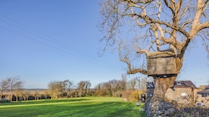 Een stenen gebouw met een houten constructie erboven, een stenen muur en een grasveld.