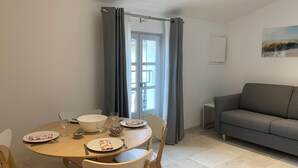 A dining area with a round table, chairs, and a grey sofa. - Holiday in Arles: Appartement de l'Amphithéâtre C (Arles)