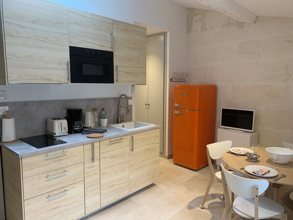 Una cocina moderna con armarios de madera, horno empotrado, un lavamanos y un comedor con mesa y sillas.