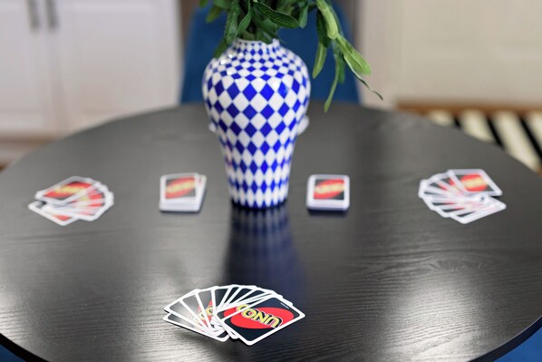 Una mesa redonda con un florero azul y blanco a cuadros en el centro, rodeada de cartas.