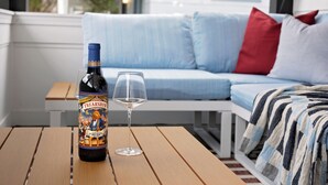 A bottle of Freakshow wine and a glass on a wooden table, with a light blue sofa and a red pillow in the background.