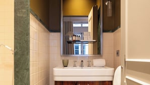 A bathroom with a marble floor, wooden vanity, white sink, and a mirror above the sink.
