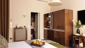 A hotel room with a bed, breakfast tray, a desk with a vase, and a view of the bathroom.