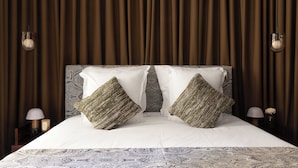 A neatly made bed with patterned bedding, two decorative pillows, and a headboard with a paisley design.