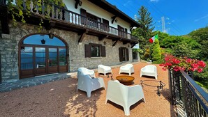 A stone building with a balcony, outdoor seating, and a flag.
