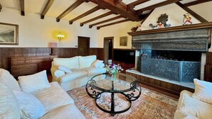 A living room with a fireplace, wooden beams, a round coffee table, and a sofa.