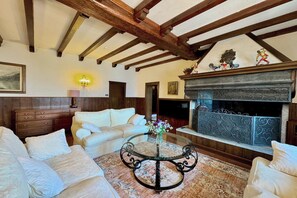 A living room with a fireplace, wooden beams, a round coffee table, and a sofa.